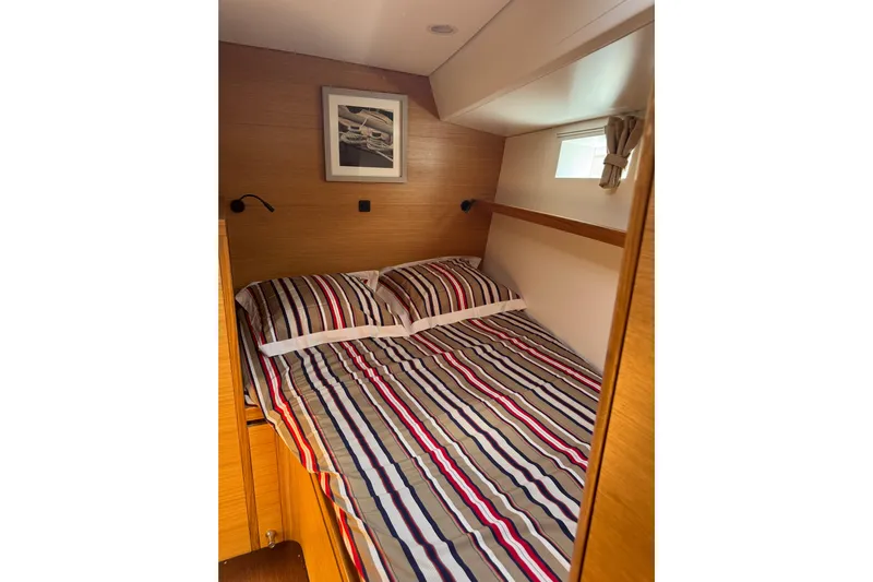  Yacht Photos Pics Cozy cabin interior of 2023 Garcia Sloop Aluminium 51 with striped bedding and wall art.