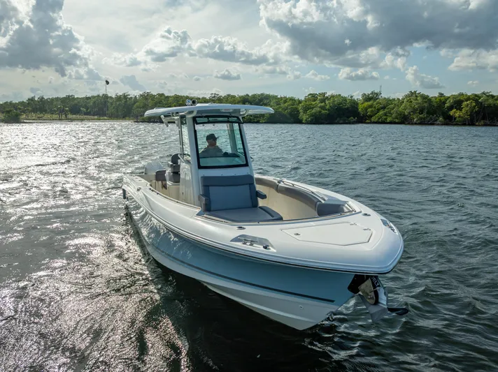 Clear To Close Yacht Photos Pics 2023 Boston Whaler 280 Outrage cruising on a scenic waterway under a cloudy sky.