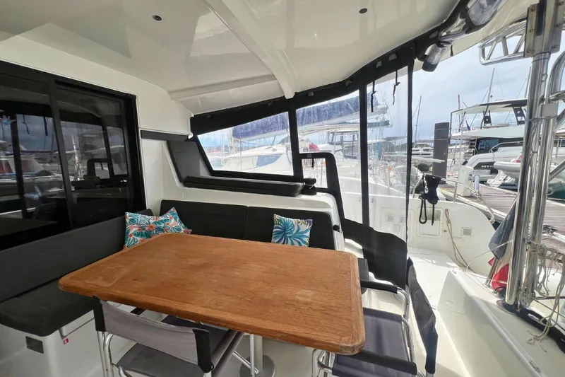 Ile En Ile Yacht Photos Pics Spacious outdoor seating area on 2018 Lagoon 42 catamaran with wooden table and cushions.