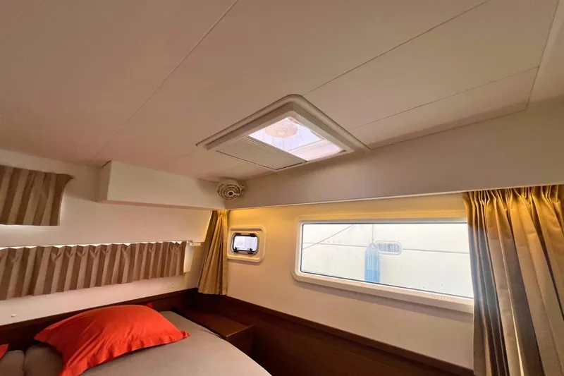 Ile En Ile Yacht Photos Pics Interior cabin of 2018 Lagoon 42 catamaran with bed, window, and curtains.