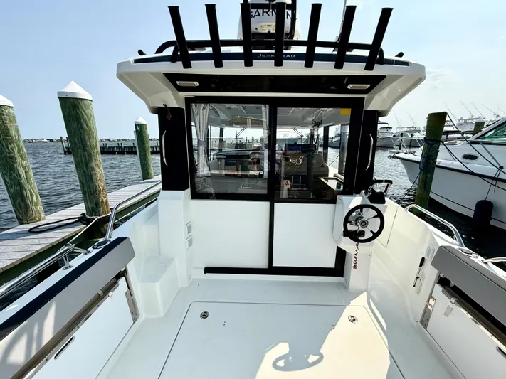  Yacht Photos Pics 2020 Jeanneau NC Sport 895 boat docked, rear view with open cockpit and steering wheel.