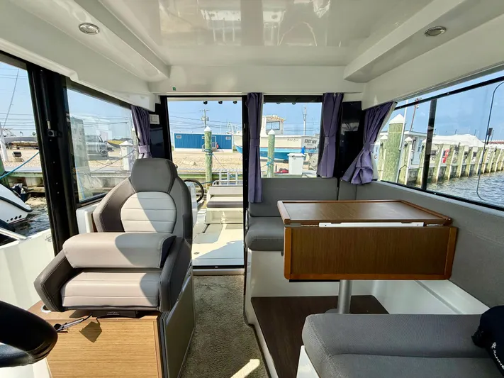  Yacht Photos Pics Interior of 2020 Jeanneau NC Sport 895 boat with seating and table, dockside view.