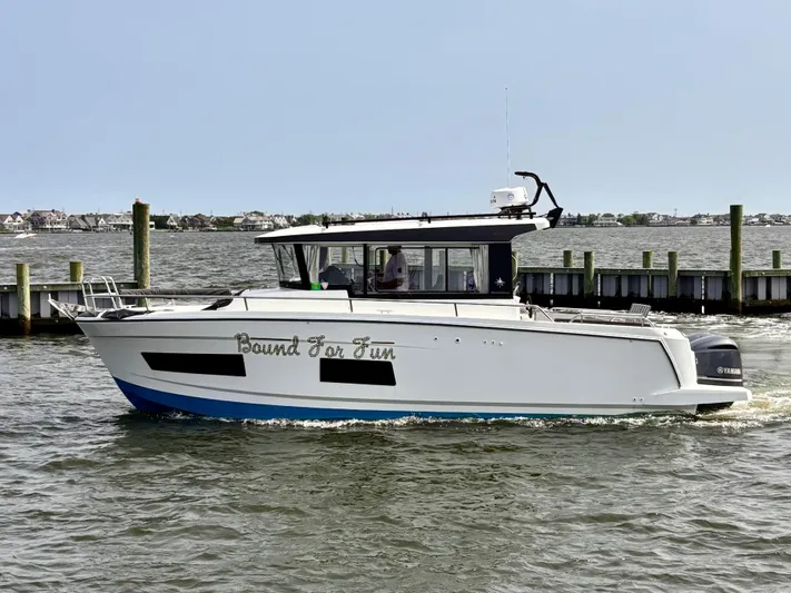  Yacht Photos Pics 2020 Jeanneau NC Sport 895 boat cruising on a calm waterway near a dock.