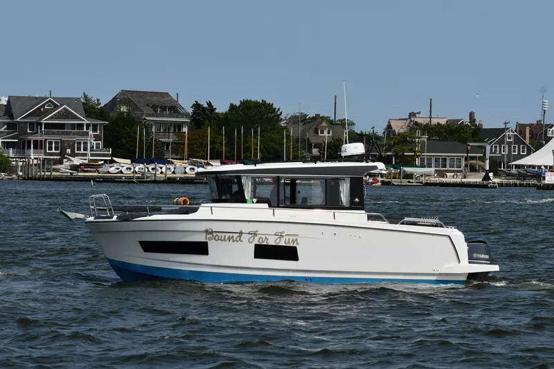  Yacht Photos Pics 2020 Jeanneau NC Sport 895 boat cruising near coastal homes.