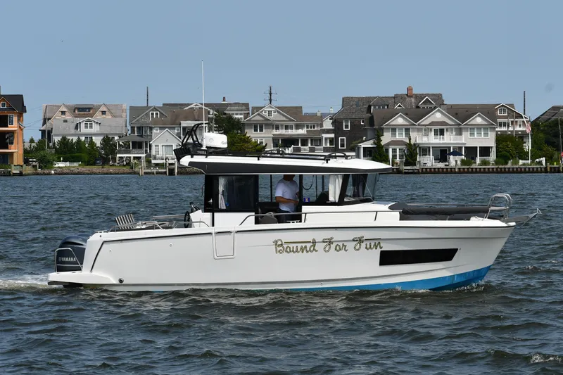  Yacht Photos Pics 2020 Jeanneau NC Sport 895 boat cruising on water near waterfront homes.