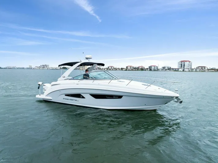 Snuffleupagus Yacht Photos Pics 2020 Regal 33 XO boat cruising on calm water with cityscape background.