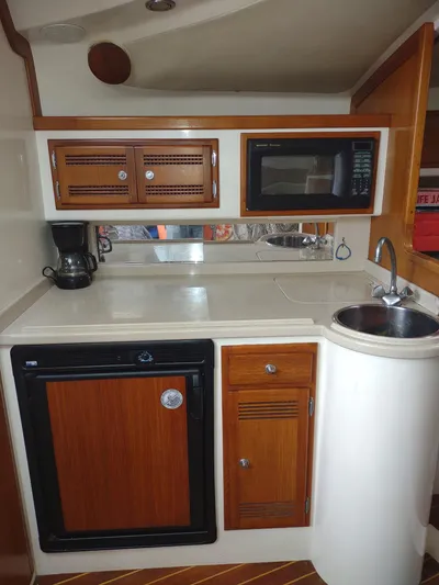 Yacht Photos Pics Compact kitchen in 1998 Cabo 31 Express boat with wood cabinets, microwave, and sink.