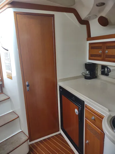  Yacht Photos Pics 1998 Cabo 31 Express yacht interior with kitchenette, wooden cabinets, and stairs.