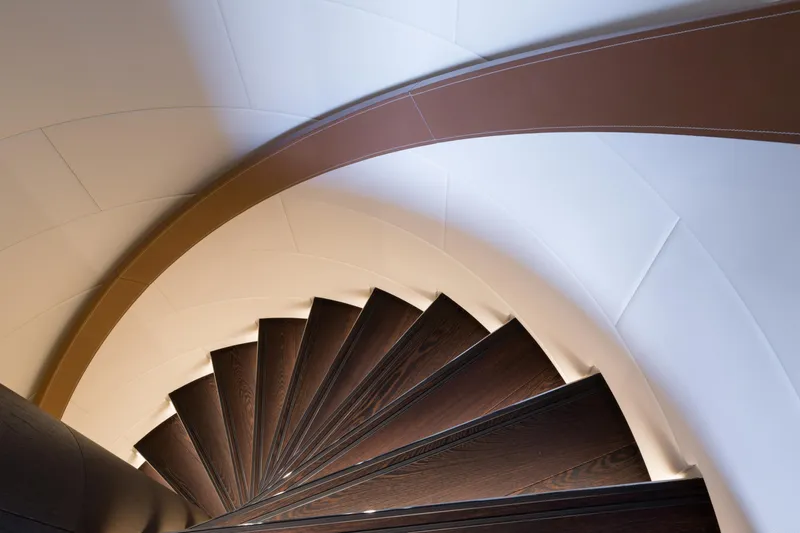 Laurentia Yacht Photos Pics Spiral staircase on 2017 Heesen Fast Displacement Motor Yacht, featuring elegant wood and leather design.