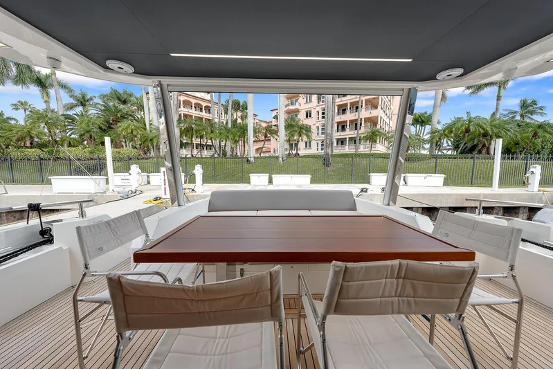 Ascendo Yacht Photos Pics Astondoa 66 yacht 2022, elegant outdoor dining area with wooden table and chairs.