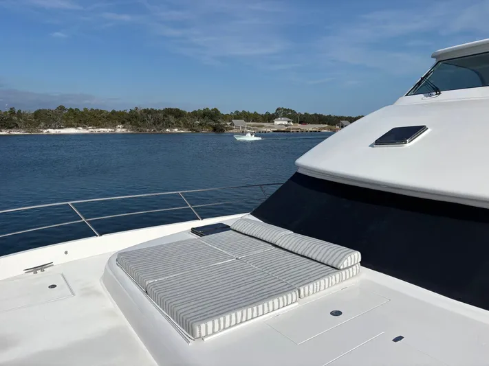 Hideout Yacht Photos Pics Luxury Horizon PC65 yacht deck with sunbed, 2022 model, overlooking serene waters and distant shoreline.