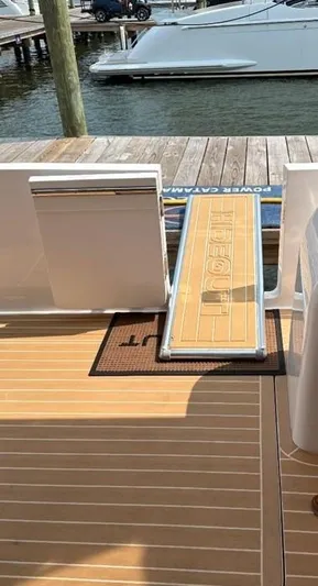 Hideout Yacht Photos Pics Luxury yacht deck with a ramp, Horizon PC65, 2022 model, docked at a marina.