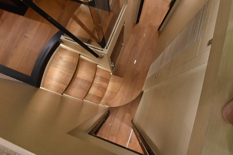 Hideout Yacht Photos Pics Curved wooden staircase inside 2022 Horizon PC65 yacht, featuring sleek modern design.