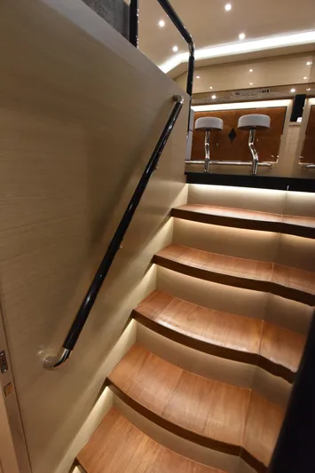 Hideout Yacht Photos Pics Luxurious wooden staircase inside 2022 Horizon PC65 yacht with modern lighting and bar stools.