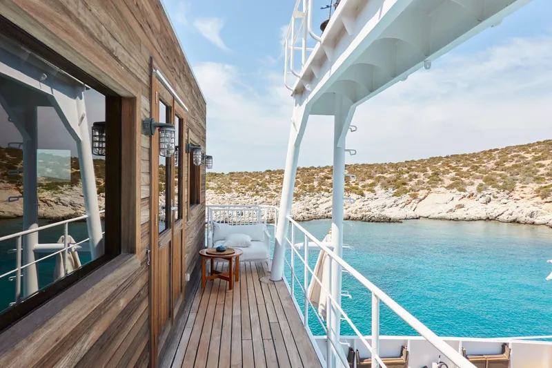 Hayama Yacht Photos Pics Wooden deck of 1988 Custom Hakodate Shipyard yacht overlooking turquoise waters and rocky coastline.