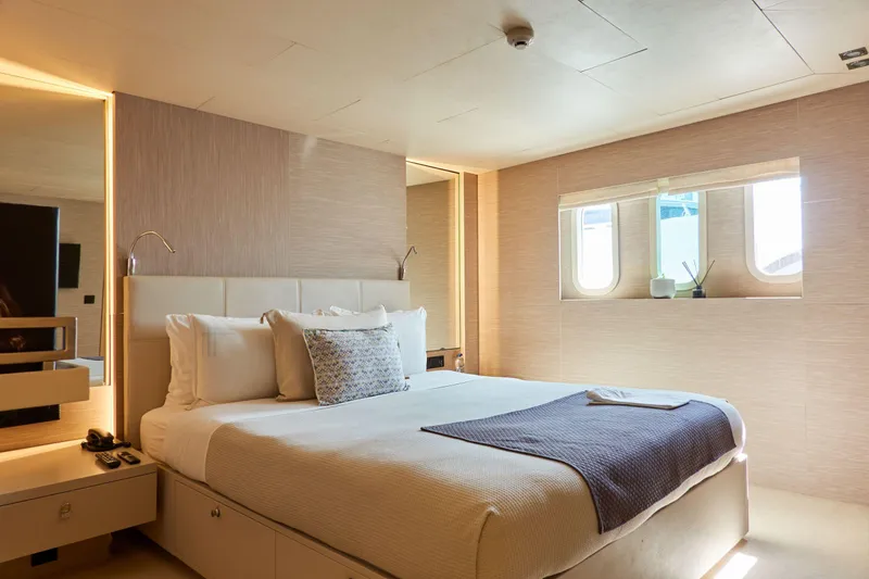 Hayama Yacht Photos Pics Luxurious ship cabin with a comfortable bed, modern decor, and natural light from windows.