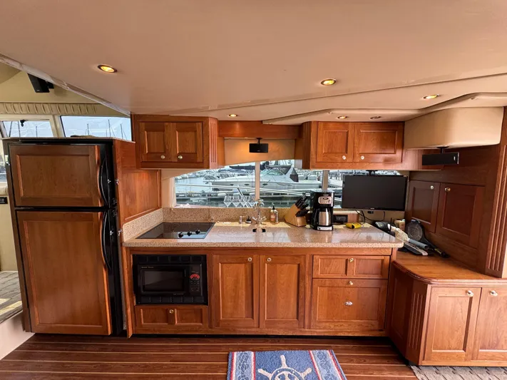 Tenacious Yacht Photos Pics Luxurious kitchen interior of 2003 Cruisers Yachts 5000 Sedan Sport with wooden cabinetry.