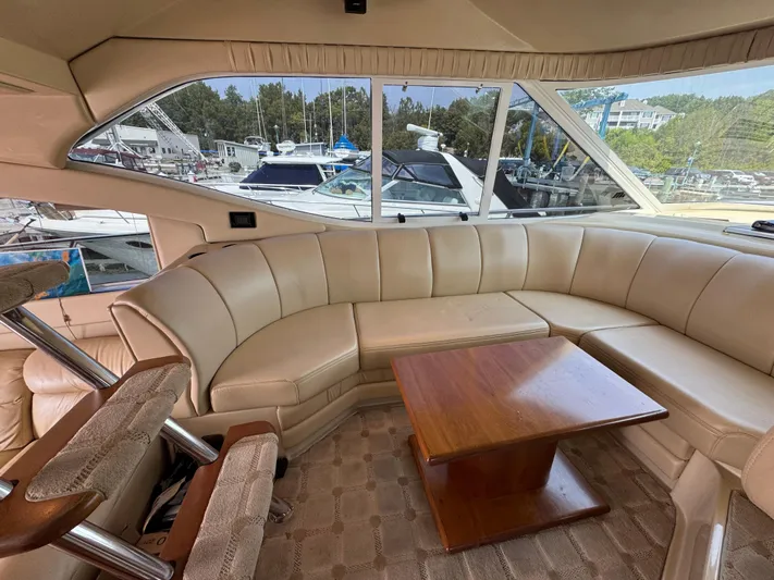 Tenacious Yacht Photos Pics Luxurious interior of 2003 Cruisers Yachts 5000 Sedan Sport with leather seating and wooden table.