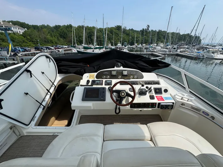Tenacious Yacht Photos Pics 2003 Cruisers Yachts 5000 Sedan Sport helm with marina view in the background.