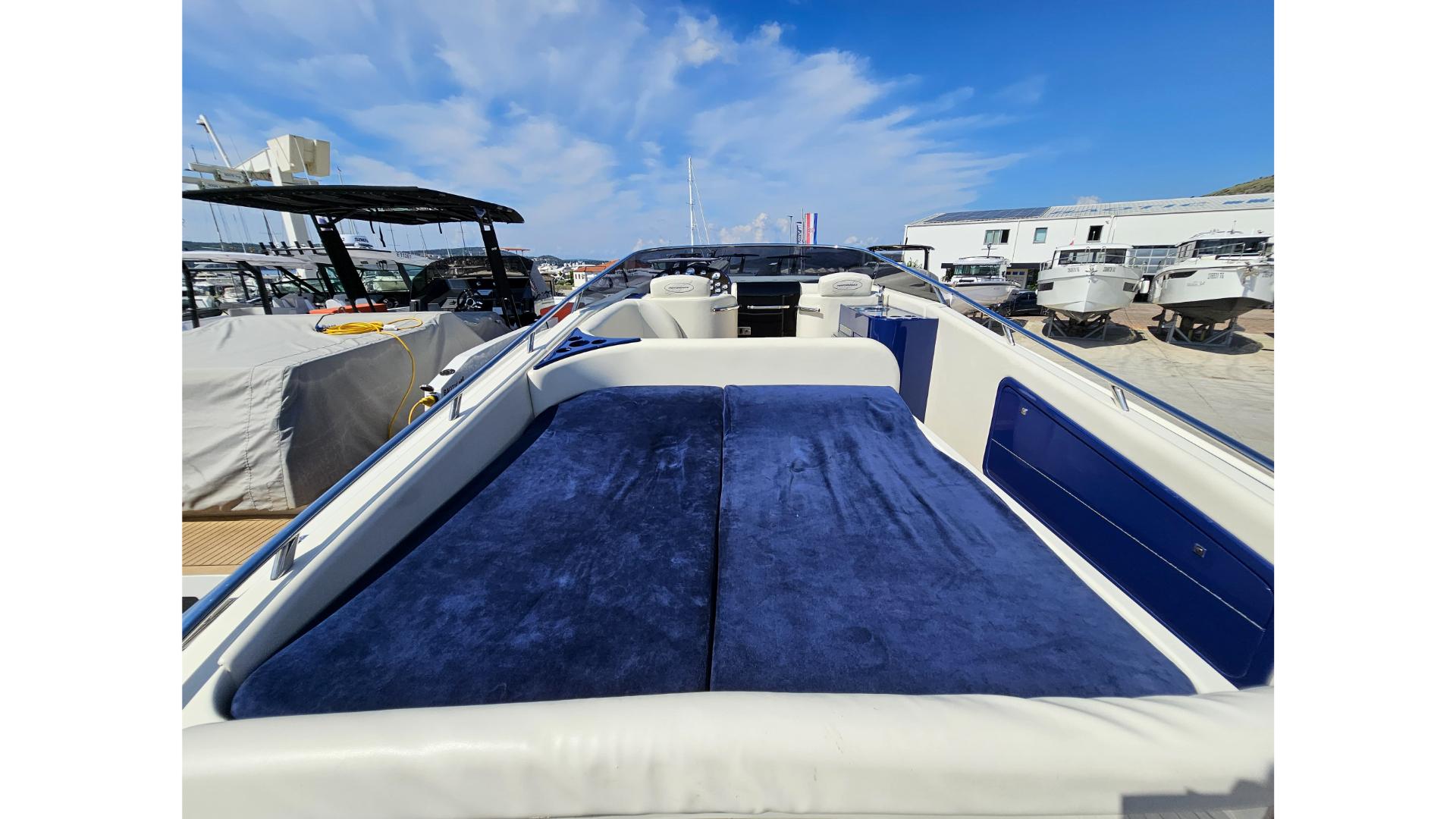 2010 Performance 1107 boat with blue seating, docked under a clear sky.