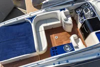 Luxurious 2010 Performance 1107 boat interior with blue and white seating, wooden deck, and modern controls.