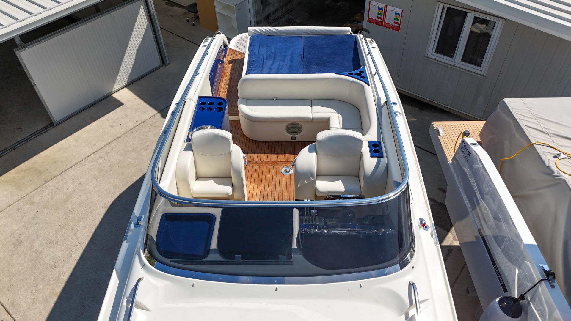 Performance 1107 boat, 2010 model, with white seating and wooden deck, docked near buildings.