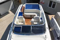 Performance 1107 boat, 2010 model, with white seating and wooden deck, docked near buildings.