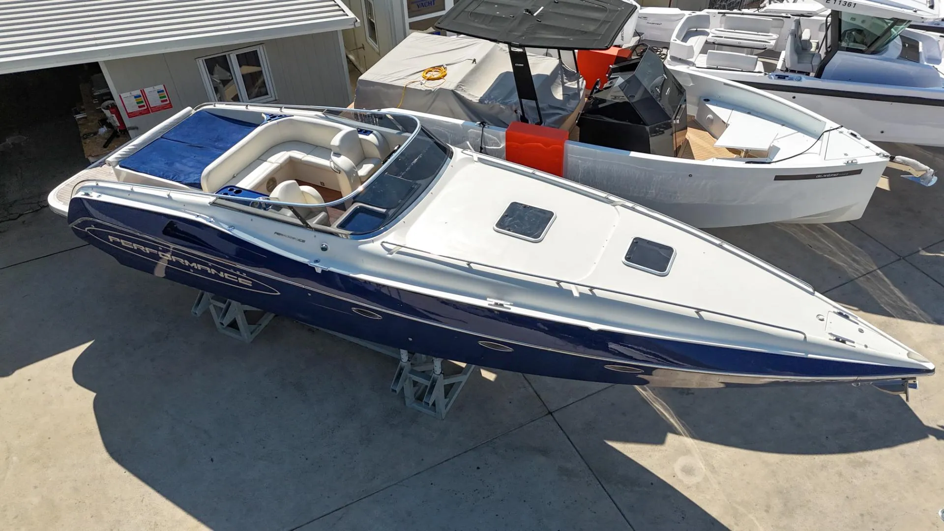 A 2010 Performance 1107 speedboat with a sleek blue and white design, docked outdoors.