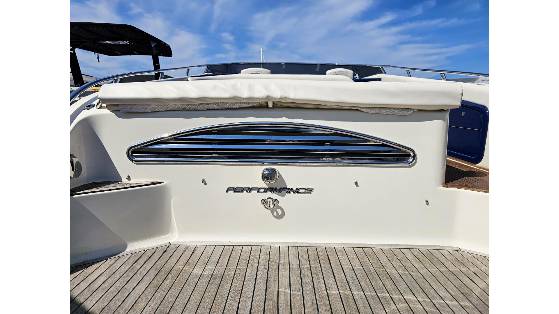 2010 Performance 1107 boat stern with chrome details and wooden deck under blue sky.