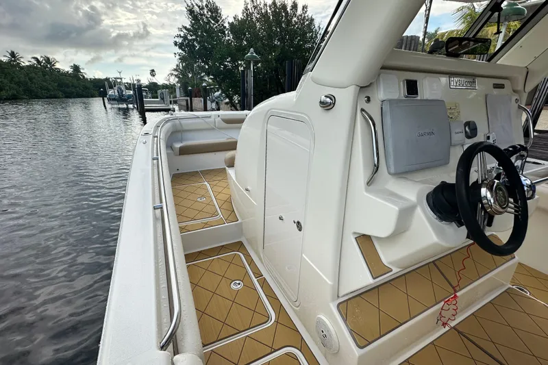  Yacht Photos Pics 2009 Mamba 350 boat interior with steering wheel and Garmin equipment, docked by a serene waterway.
