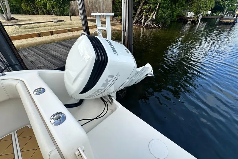  Yacht Photos Pics Boat with Suzuki outboard motor docked by a wooden pier, surrounded by water and greenery.