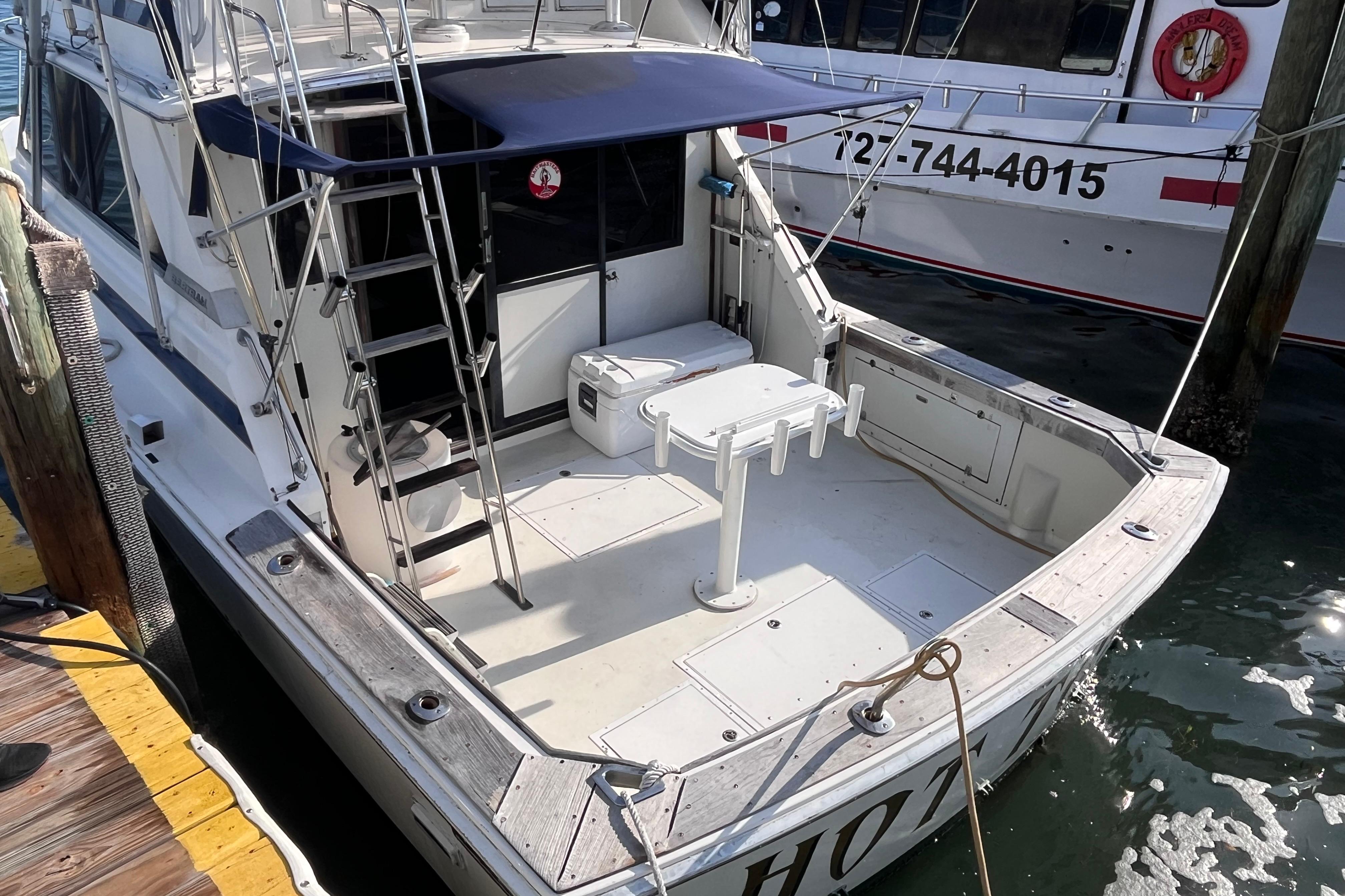 1981 Bertram 35 Sportfish boat docked, featuring spacious deck and ladder.