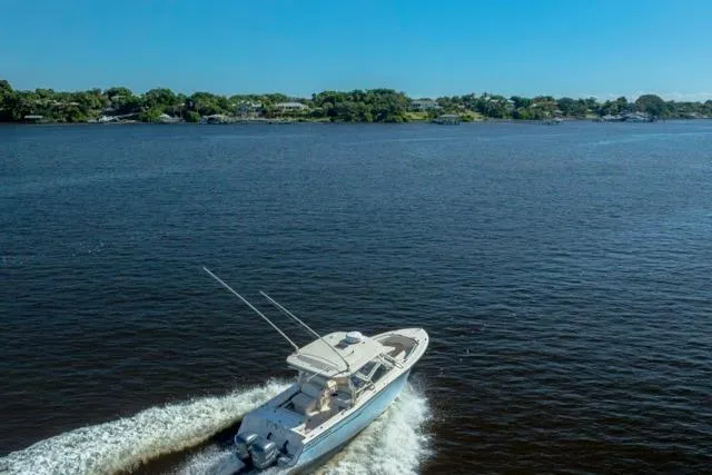  Yacht Photos Pics 2017 Grady-White Freedom 307 boat cruising on a serene lake under a clear blue sky.