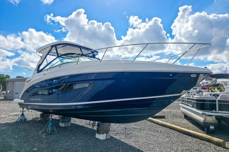  Yacht Photos Pics 2026 Regal 33 XO boat on stands under a bright blue sky with clouds.