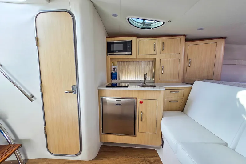  Yacht Photos Pics 2026 Regal 33 XO yacht interior with kitchenette, wooden cabinets, and seating area.