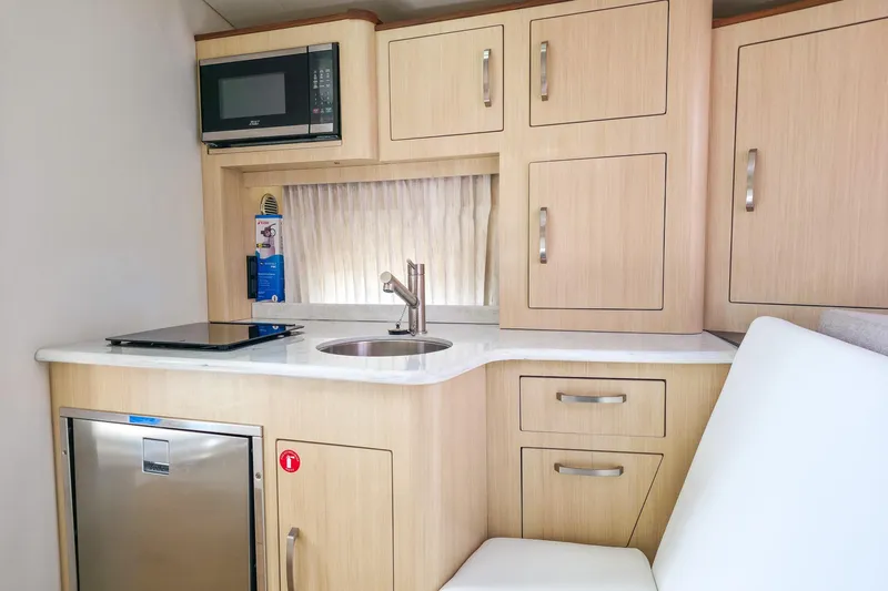  Yacht Photos Pics 2026 Regal 33 XO boat interior kitchen with microwave, sink, and wooden cabinets.