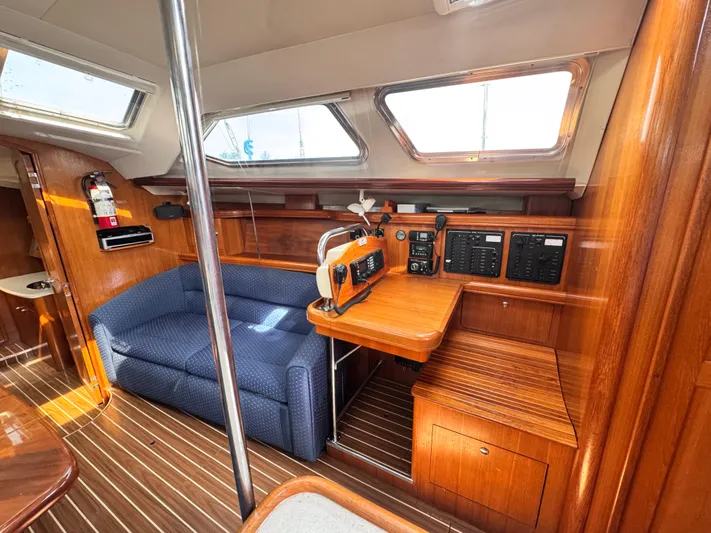 Stormcat Yacht Photos Pics 2006 Hunter 41 Deck Salon interior with wood finish, blue sofa, and navigation equipment.