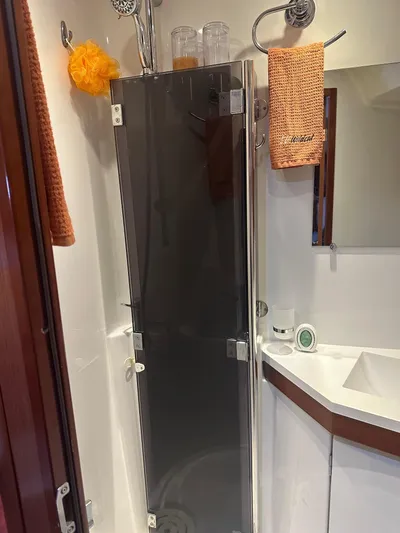  Yacht Photos Pics Beneteau Oceanis 50 bathroom with glass shower door, orange towels, and modern fixtures, 2014 model.