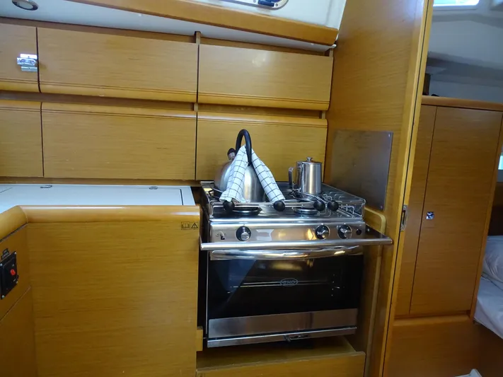 Sea Sea Rider Yacht Photos Pics 2017 Jeanneau Sun Odyssey 389 yacht kitchen with stove, oven, and wooden cabinetry.