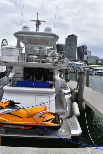  Yacht Photos Pics 2018 Azimut Flybridge yacht docked with orange jet ski, city skyline in background.