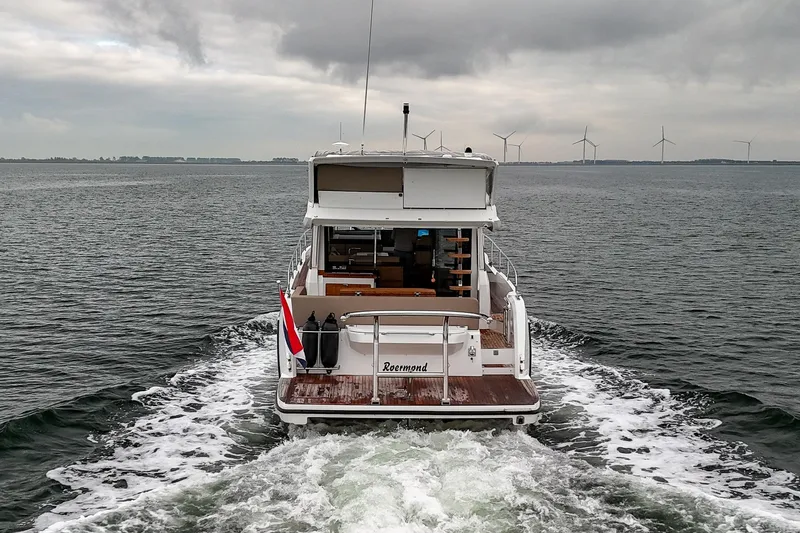  Yacht Photos Pics 2021 Sealine F430 yacht cruising on open water with wind turbines in the background.