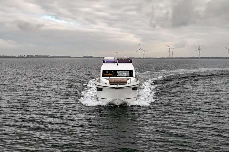  Yacht Photos Pics 2021 Sealine F430 yacht cruising on open water with wind turbines in background.