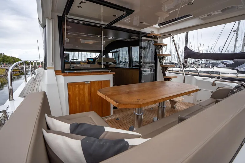 Yacht Photos Pics 2021 Sealine F430 yacht interior with wooden table, seating, and marina view.
