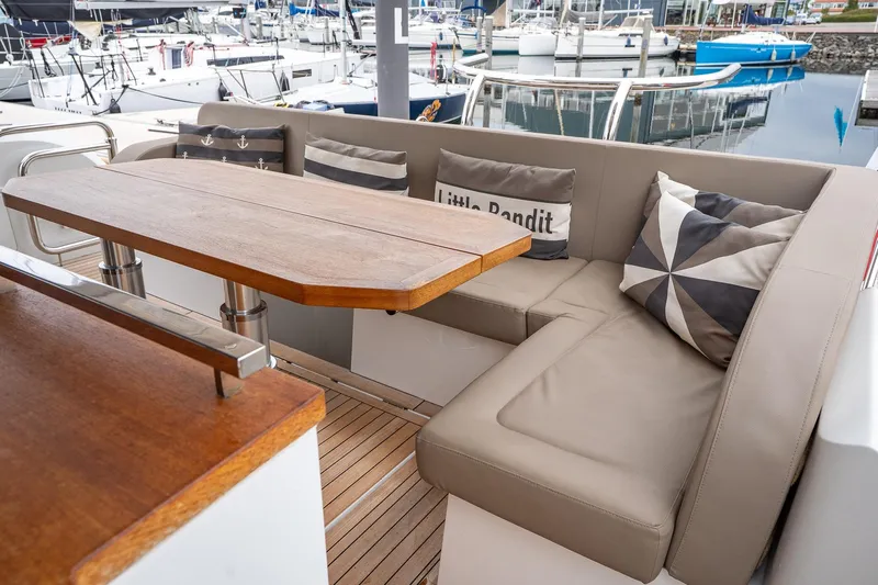  Yacht Photos Pics 2021 Sealine F430 yacht interior with cozy seating and wooden table in marina setting.
