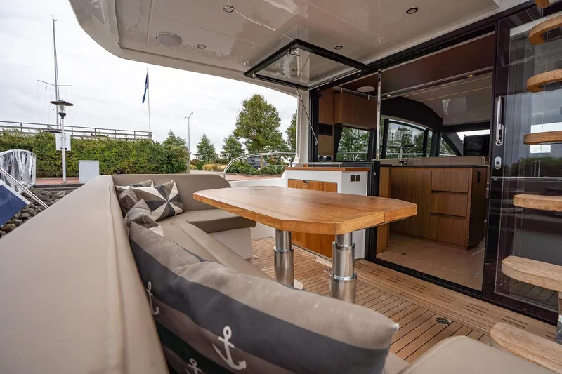  Yacht Photos Pics 2021 Sealine F430 yacht interior with wooden table, cushioned seating, and modern kitchen.