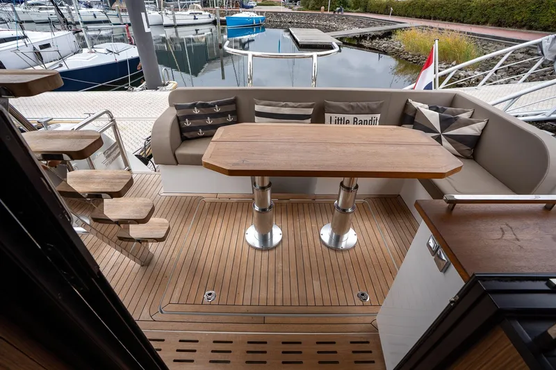  Yacht Photos Pics Luxurious 2021 Sealine F430 yacht deck with wooden table and cushioned seating.
