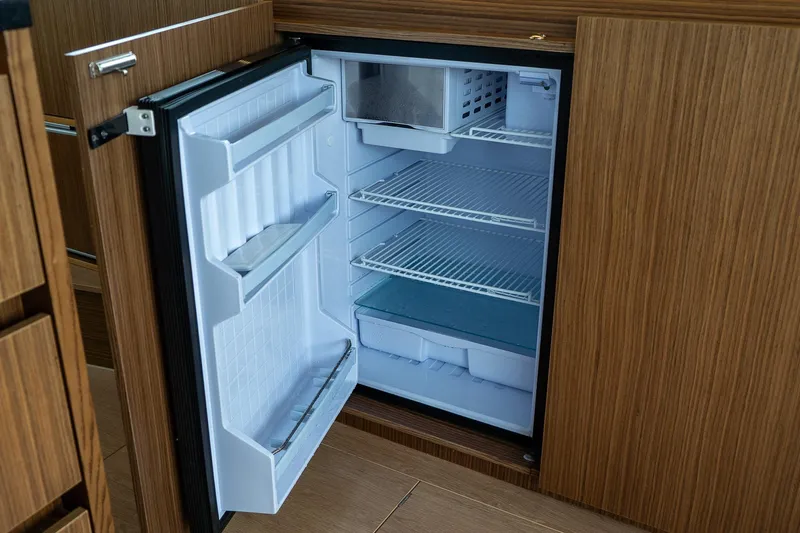  Yacht Photos Pics Open refrigerator inside 2021 Sealine F430 yacht, featuring wooden cabinetry and spacious shelving.