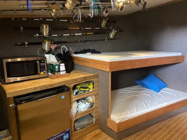 Waverunner Yacht Photos Pics 2022 Custom Carolina Sportfish interior with bunk beds, fishing rods, microwave, and mini-fridge.
