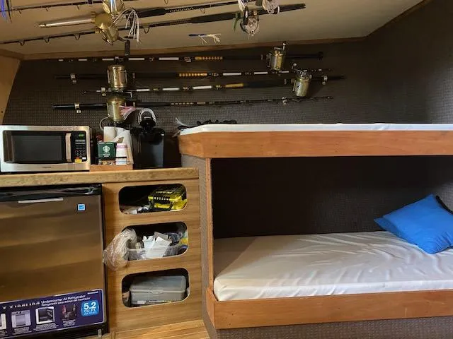 Waverunner Yacht Photos Pics Interior of 2022 Custom Carolina Sportfish with bunk beds, fishing rods, microwave, and mini-fridge.