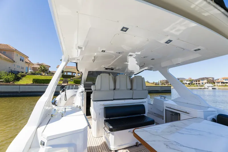 Loki Yacht Photos Pics 2018 Azimut Verve 40 yacht interior with seating and table, docked near waterfront homes.